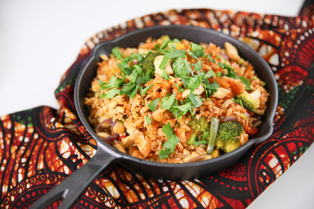 Skillet filled with spiced rice and vegetables, garnished with fresh herbs, resting on a colorful patterned cloth.